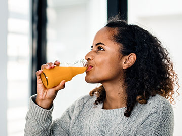 Woman enjoying fresh orange juice on a school morning