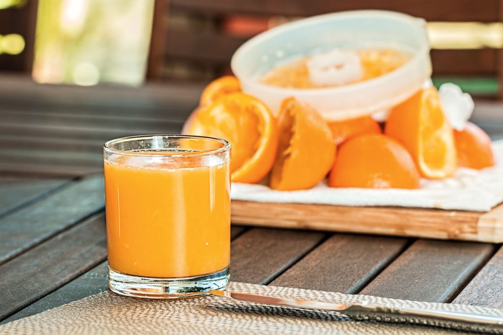 A fresh glass of orange juice next to squeezed orange halves, representing the natural energy boost of orange juice